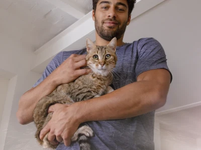 Seorang pria sedang menggendong kucing 