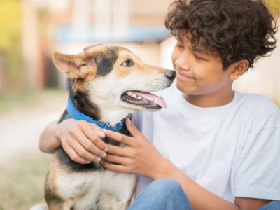 A boy plays with his dog outside.