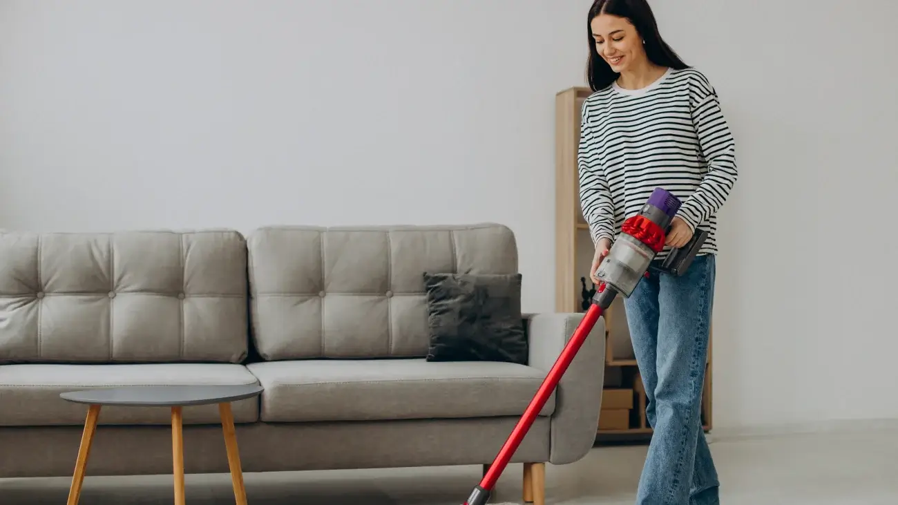 A woman vacuuming her bedroom in the daytime