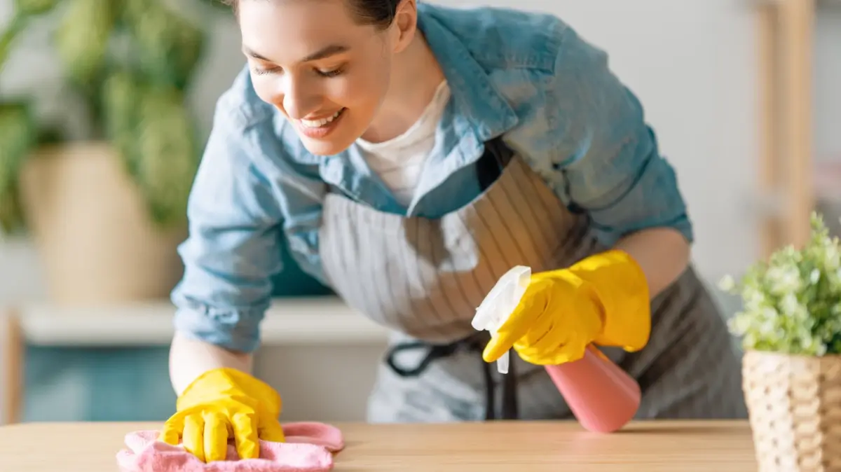 A woman wears gloves while cleaning.