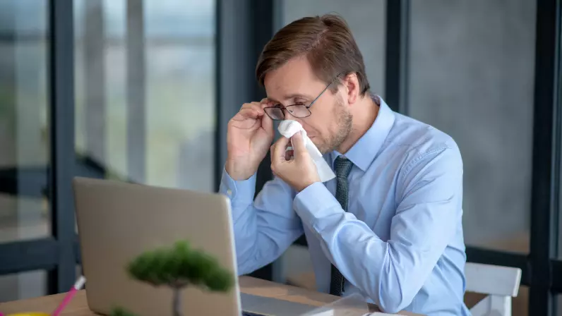 Businessman trying to clear a blocked and stuffy nose